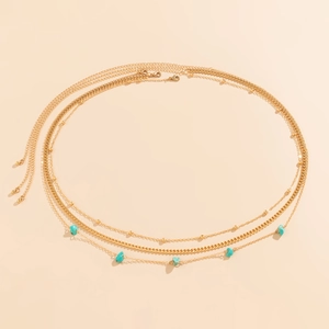 Detailed view of bohemian triple-layered gold waist chain with turquoise stone pendants