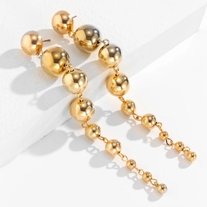 Punk style golden ball drop earrings with polished cascading spheres on white stand