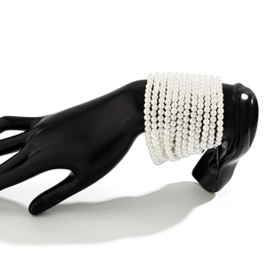 Primer plano de pulsera de perlas blancas multicapa sobre exhibidor de mano negra