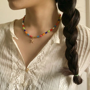 Nahaufnahme einer bunten Perlenkette mit goldenem Seestern-Anhänger an einem Model