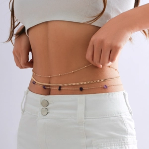 Close-up of three-layer gold body chain with purple stones on woman waist