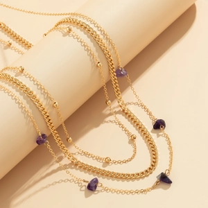 Detail of layered gold waist chain featuring purple stones and punk style metal links