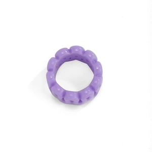 Detail view of purple resin ring with glossy wavy texture and wide hollow band