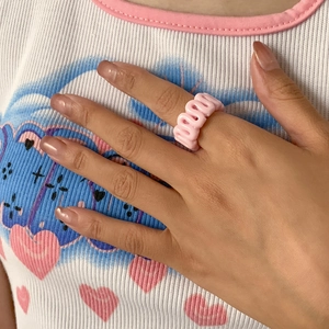 Close-up of pink wavy resin ring on finger showcasing Y2K style curved design