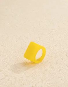 Gros plan d'une bague en acrylique jaune vif avec un large anneau géométrique carré moderne