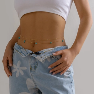 Macro detail of gold-plated double-layer waist chain with turquoise beads on model