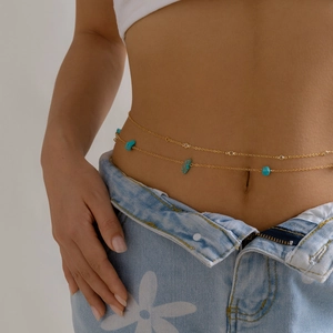 Detail of bohemian gold waist chain with turquoise stones on a female model