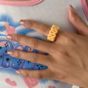 Macro shot of ginger yellow wavy resin ring showing vibrant S-shaped design on finger