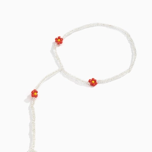 Detailed close-up of elastic beaded anklet with red and yellow daisy charms