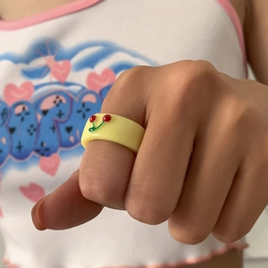 Nahaufnahme eines gelben Harzrings mit 3D-Kirschdesign am Finger getragen