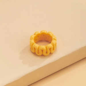 Macro shot of thick yellow resin ring with continuous wavy texture and matte finish