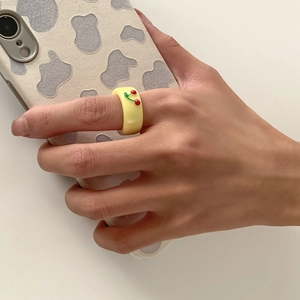 Detail eines gelben Harzrings mit 3D-Kirschdekor an der Hand am Handy gehalten