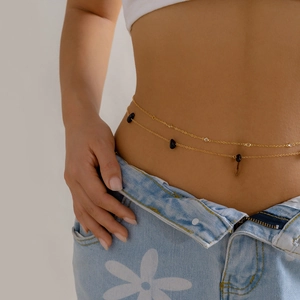 Close-up of double-layer gold waist chain with black stones and crystals on a model