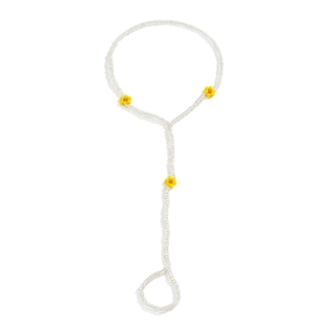 Detail of white beaded slave bracelet featuring yellow daisy charms on plain background