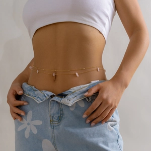 Detail of a double-layered gold body chain with pink crystal stones on a female model
