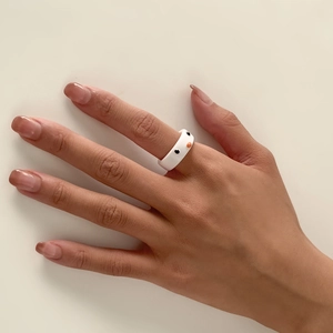 Nahaufnahme eines weißen Harzrings mit süßem Tiergesichtsmuster auf dem Zeigefinger