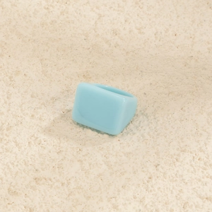 Vue rapprochée d'une bague carrée large en résine bleu clair au style minimaliste moderne
