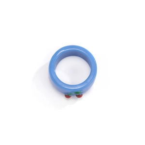 Nahaufnahme eines blauen Harzrings mit 3D-Kirschen-Anhänger und grünen Blättern am Band