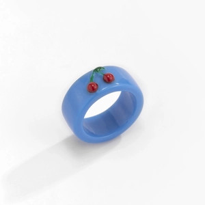 Detailansicht eines breiten blauen Harzrings mit süßer roter Kirsch-Dekoration