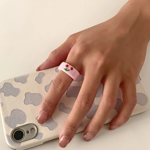 Detailaufnahme eines rosa Harzrings mit 3D-Kirschmotiv, am Finger getragen