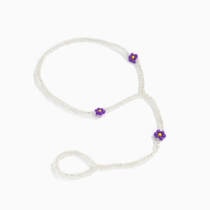 Detail of beaded daisy foot chain featuring white and purple floral seed beads pattern