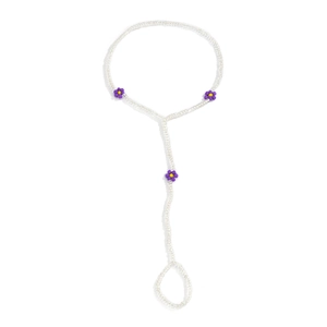 Detail of white beaded anklet with purple and yellow daisy flower accents on white background