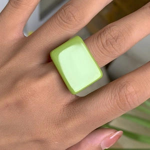 Vue macro d'une bague carrée en résine vert clair portée avec style minimaliste