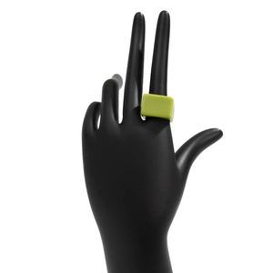 Détail macro d'une bague géométrique en résine vert herbe avec un design carré audacieux