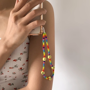 Handmade rainbow beaded phone strap with yellow smiley faces held by a model