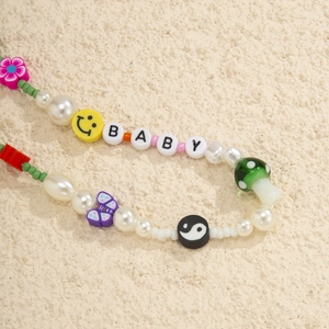 Detail of beaded phone strap with pearls, mushrooms, smiley faces and BABY letter beads