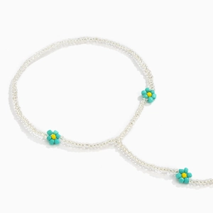 Detail of beaded anklet featuring blue daisy flowers and transparent seed beads