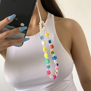 Detailed shot of handmade phone strap with faux pearls, colorful flowers and mushrooms