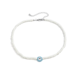 Primer plano del collar de perlas blancas con la letra H en azul y cierre plateado