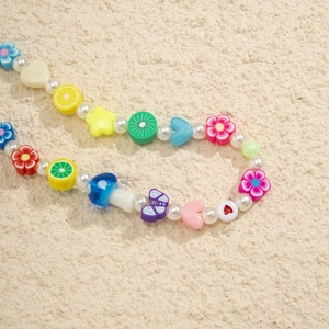 Macro shot of colorful beaded strap featuring faux pearls, fruit slices, and floral charms