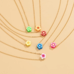 Dettaglio di ciondoli a fiore colorati su sottili catene dorate in sette tonalità vivaci