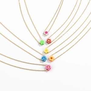Dettaglio di catene dorate boho con ciondoli a fiore in argilla in sette colori vivaci