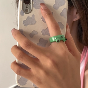 Detailansicht eines grünen Harz-Froschrings, getragen an einem Finger im Selfie-Stil