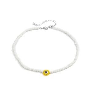 Detalle del collar de cuentas blancas con dije de flor amarilla y colgante de letra W