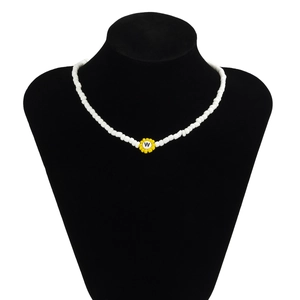 Primer plano de collar de cuentas blancas con colgante de girasol y la letra W
