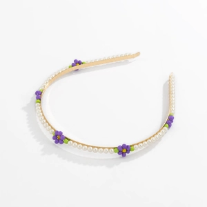 Detailed view of floral headband with white pearls and purple bead flowers on gold metal