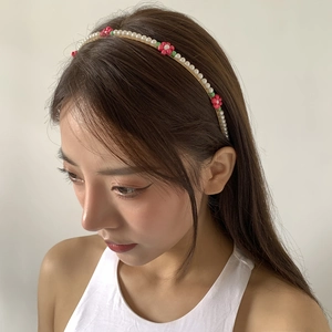 Detail of floral pearl headband featuring pink flowers and green leaves on a model