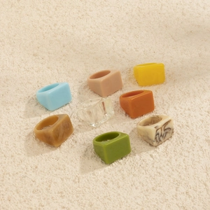 Lot de 8 bagues géométriques carrées en résine acrylique colorée sur fond de pierre naturelle