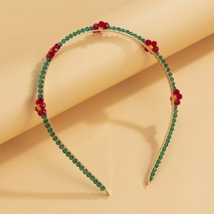 Detailed close-up of golden metal headband with red crystal flowers and green beads