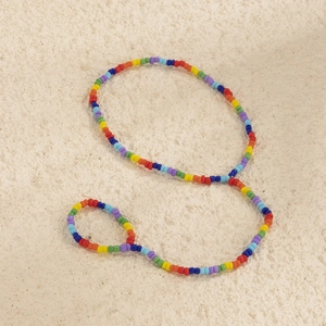 Dettaglio della cavigliera con perline arcobaleno e piccole sfere colorate vivaci