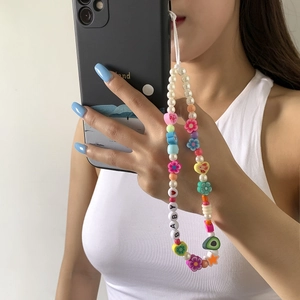 Detail showing colorful polymer clay flower beads and pearl phone charm strap on device