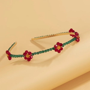 Detail of floral headband with red and green crystals on a gold-tone metallic base