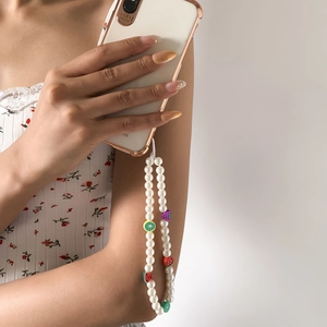 Detail of beaded phone strap with white pearls and colorful lime strawberry fruit charms