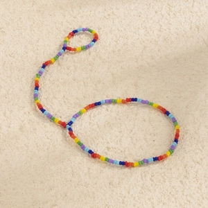 Dettaglio ravvicinato della cavigliera con perline arcobaleno su sfondo minimalista