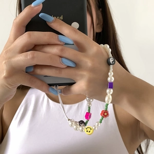 Close-up of beaded phone strap with pearls, colorful flower beads and smiley charms