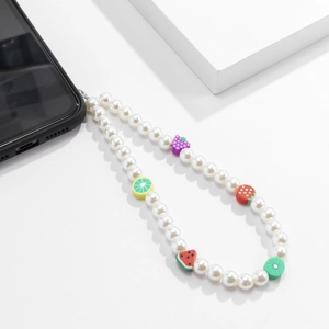 Détail de dragonne pour téléphone avec perles blanches et charms de fruits en pâte polymère